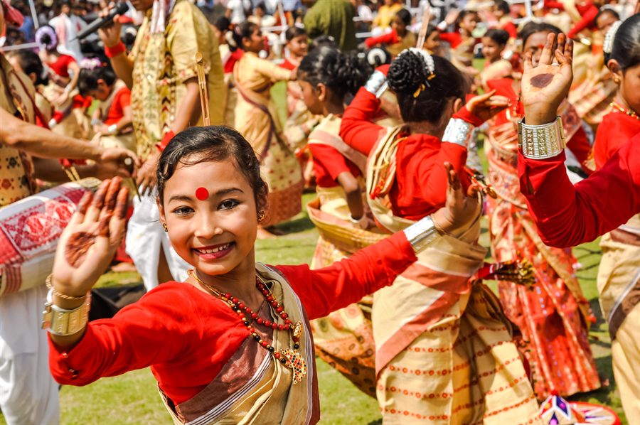 Dancers in red and gold costume performing the Bihu dance of Assam